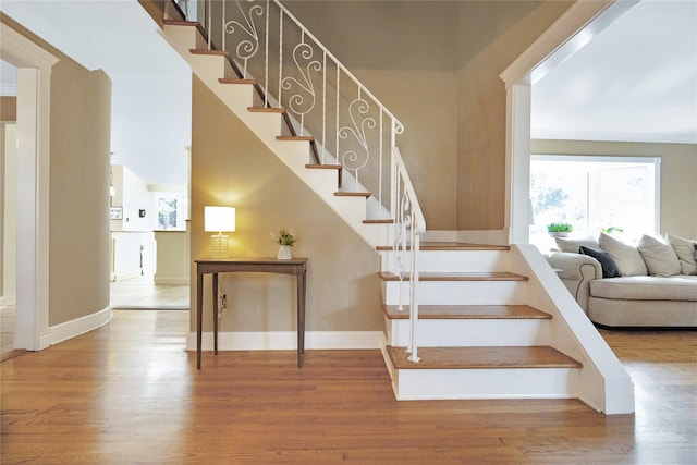 stairs with hardwood / wood-style floors and crown molding