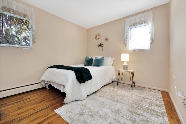 bedroom featuring hardwood / wood-style flooring and a baseboard heating unit