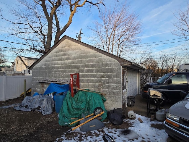 snow covered property featuring a garage and an outbuilding