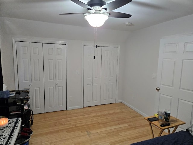 bedroom featuring ceiling fan, two closets, and light wood-type flooring