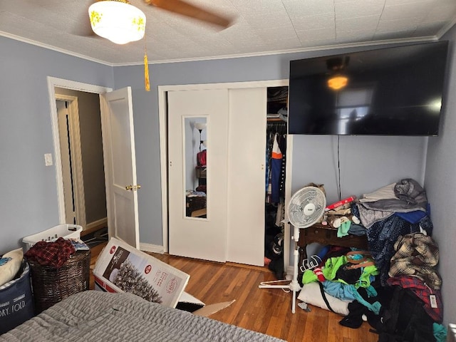 bedroom featuring ornamental molding, hardwood / wood-style floors, ceiling fan, and a closet