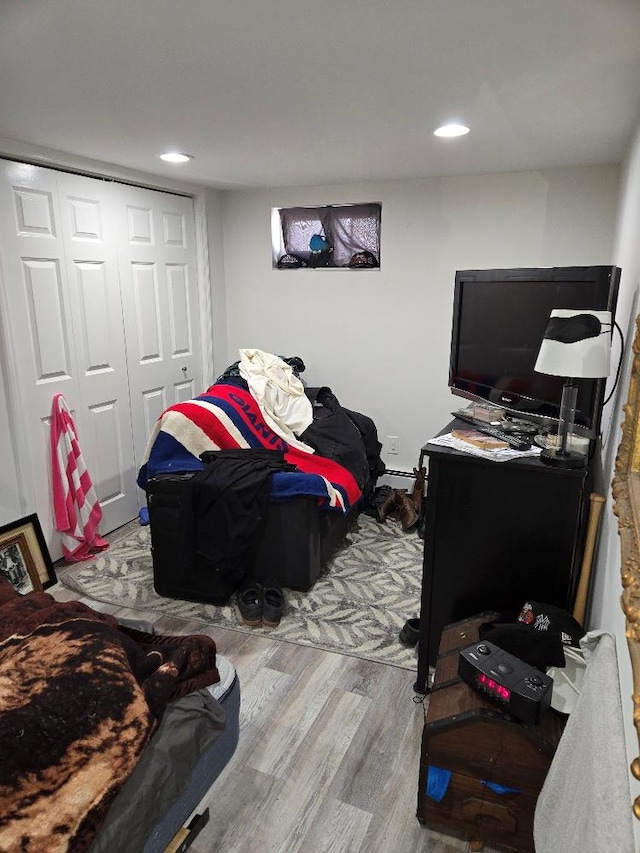 bedroom featuring a baseboard heating unit, wood-type flooring, and a closet