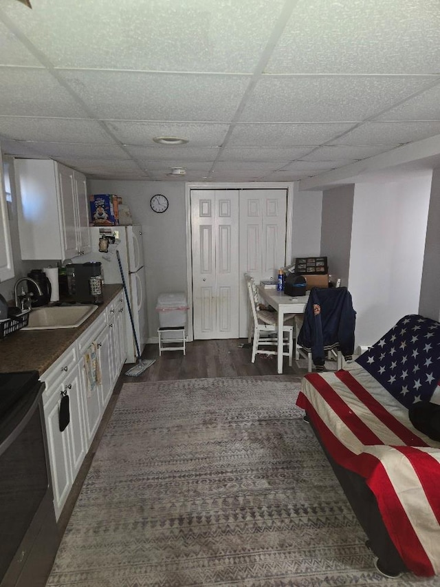 kitchen with dark hardwood / wood-style floors, a paneled ceiling, sink, white cabinets, and electric stove