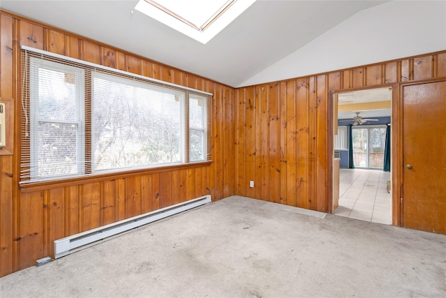 carpeted spare room featuring lofted ceiling with skylight, a healthy amount of sunlight, ceiling fan, and baseboard heating