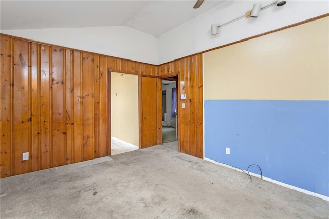 empty room featuring lofted ceiling, light colored carpet, and wood walls