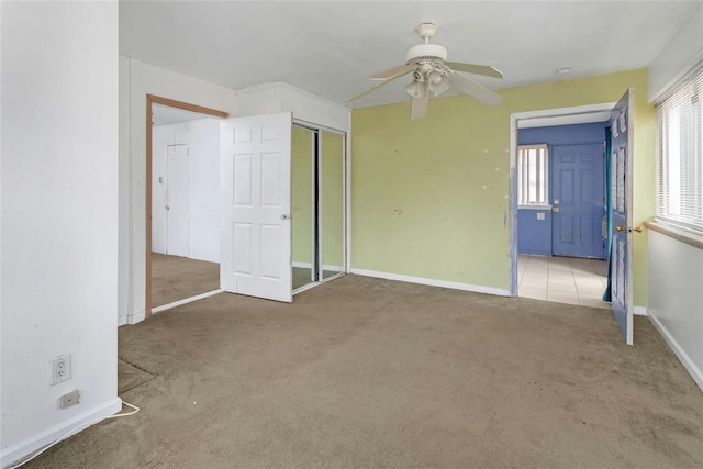 unfurnished bedroom with multiple windows, light colored carpet, ceiling fan, and a closet