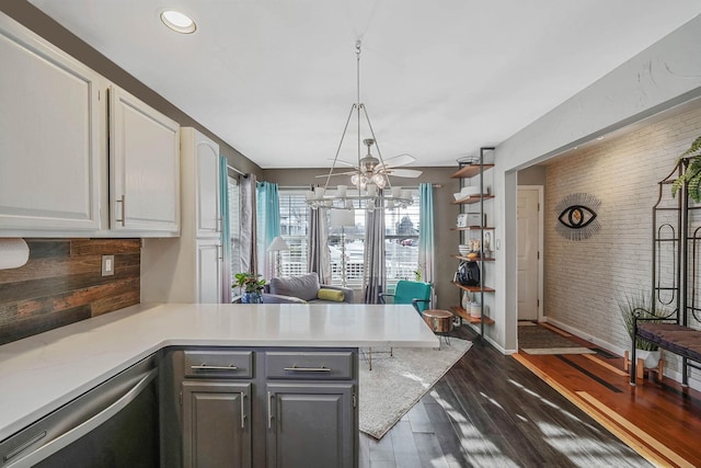 kitchen with brick wall, stainless steel dishwasher, white cabinets, and kitchen peninsula