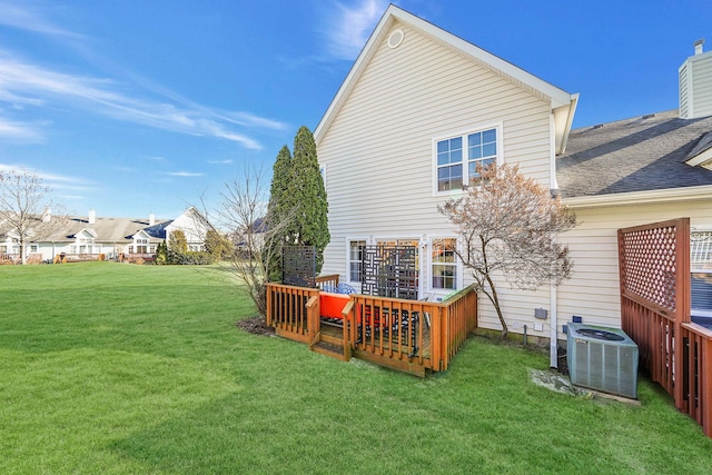 back of property with a wooden deck, a yard, and cooling unit