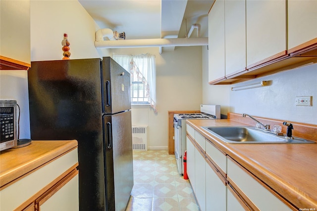 kitchen featuring white cabinetry, appliances with stainless steel finishes, sink, and radiator