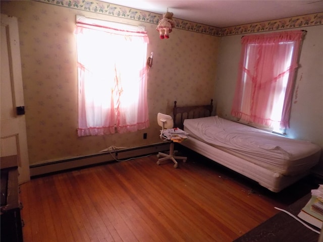 unfurnished bedroom with a baseboard radiator and wood-type flooring