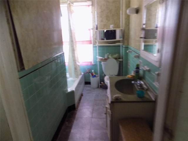 full bathroom with tile patterned floors, shower / bath combination, tile walls, and a wealth of natural light