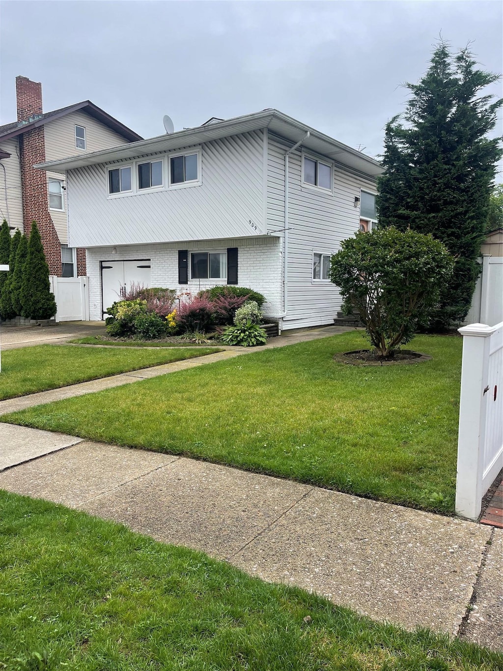 909 N Central Ave, Woodmere, NY 11598 - view of property exterior featuring brick siding and a yard