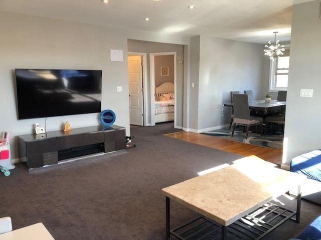 carpeted living room with an inviting chandelier