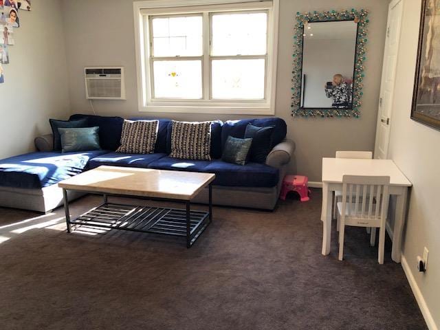 living room featuring a wall unit AC and dark carpet