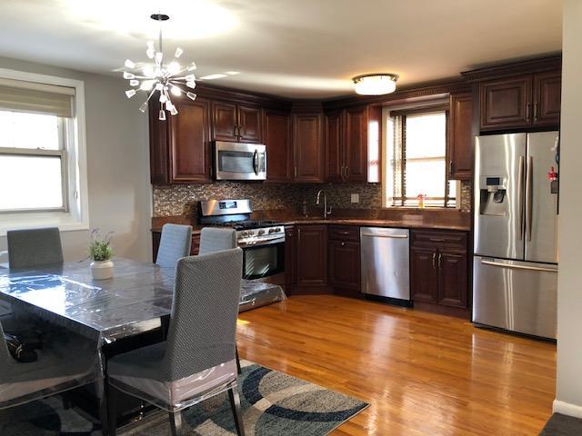 kitchen with an inviting chandelier, light hardwood / wood-style flooring, stainless steel appliances, and a healthy amount of sunlight