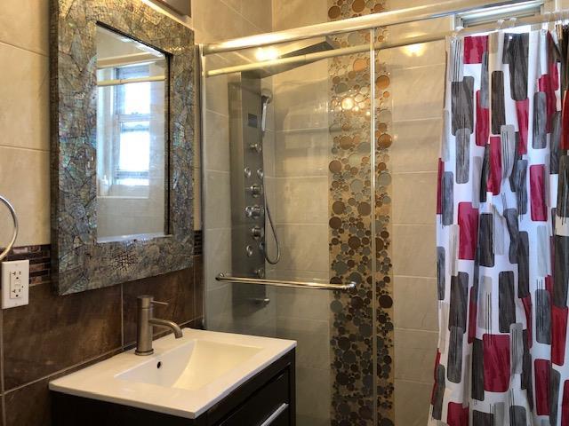 bathroom with vanity, a shower with shower curtain, and tile walls