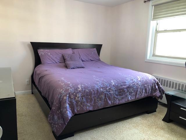 carpeted bedroom featuring radiator