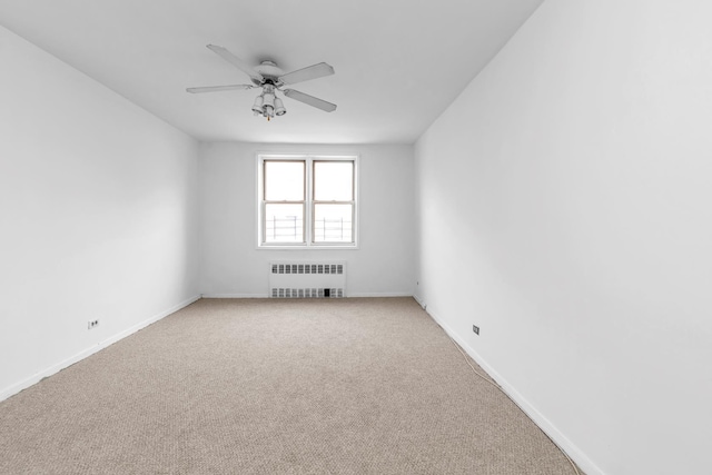 carpeted spare room featuring ceiling fan and radiator