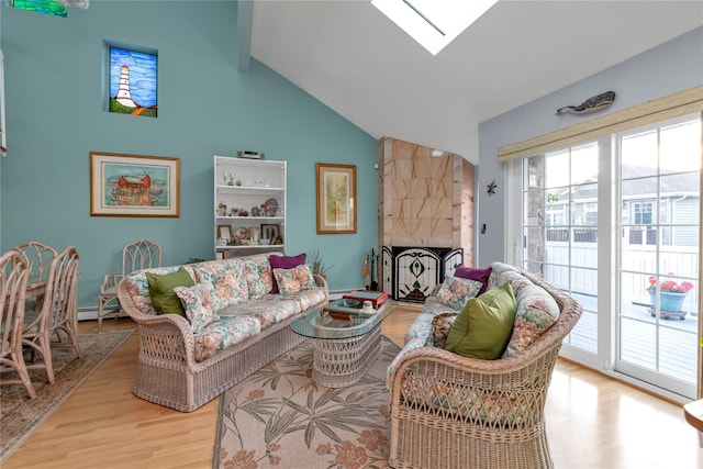 living room featuring a baseboard heating unit, lofted ceiling with skylight, light hardwood / wood-style floors, and a large fireplace