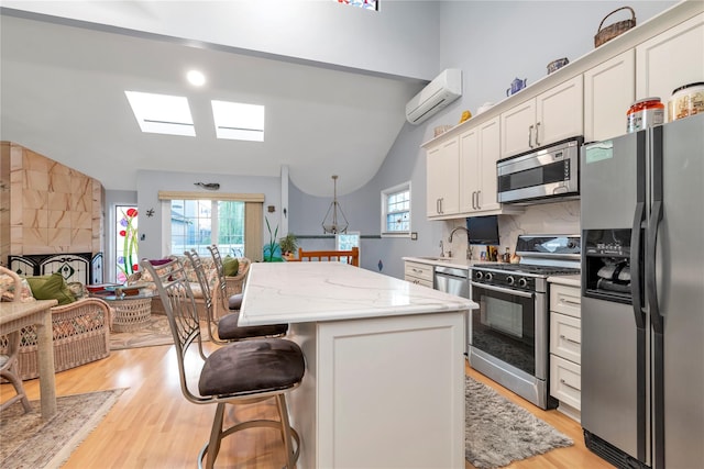 kitchen featuring an AC wall unit, a kitchen island, stainless steel appliances, decorative backsplash, and white cabinets