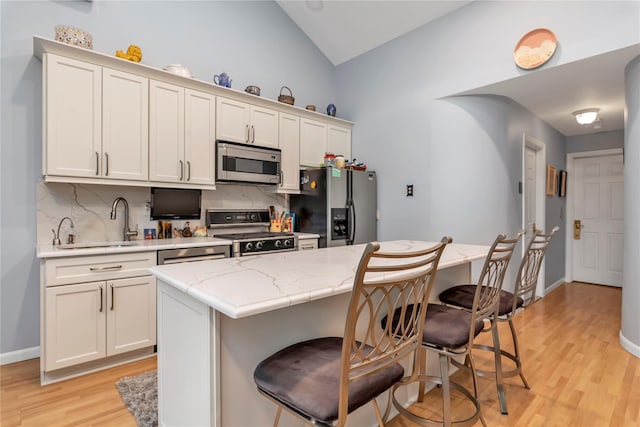 kitchen featuring a kitchen island, lofted ceiling, backsplash, a kitchen breakfast bar, and stainless steel appliances