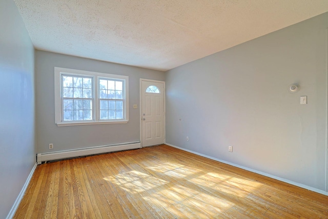 interior space featuring light hardwood / wood-style floors, a textured ceiling, and a baseboard heating unit