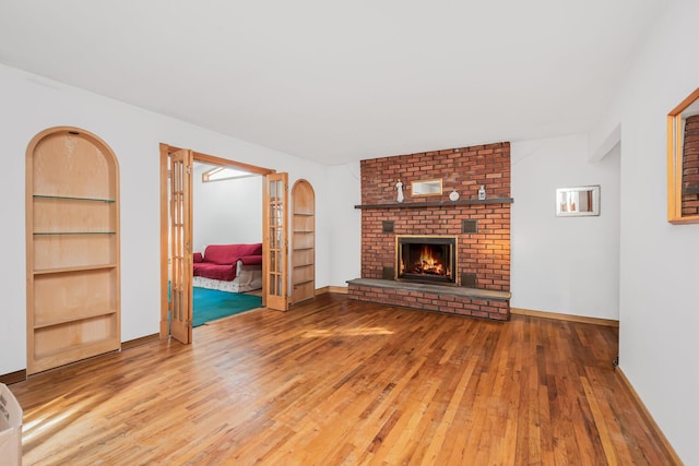 unfurnished living room with hardwood / wood-style flooring, a fireplace, and built in features