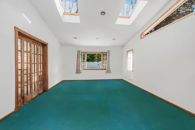 carpeted spare room featuring vaulted ceiling with skylight