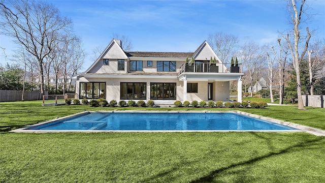 rear view of house featuring a fenced in pool, a yard, and a balcony