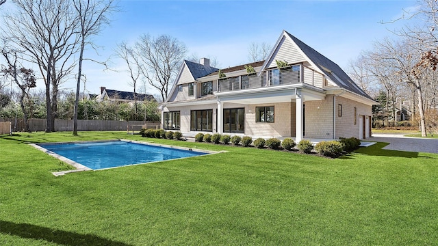 back of house featuring a fenced in pool, a balcony, and a yard