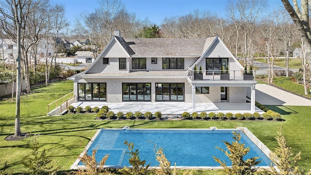 rear view of house featuring a balcony, a patio, and a lawn