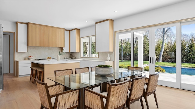 kitchen featuring french doors, a center island, light brown cabinets, light wood-type flooring, and backsplash