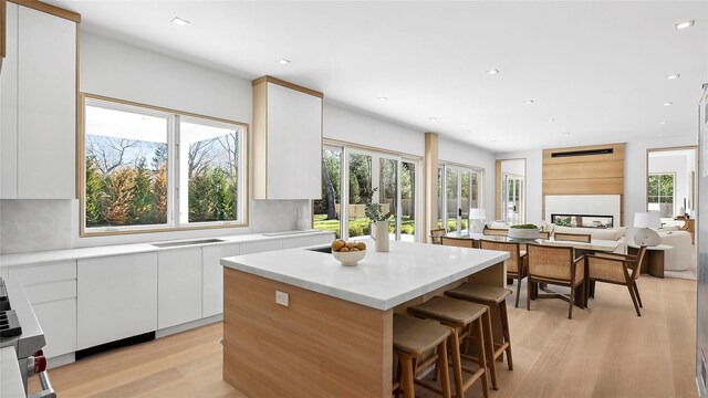 kitchen featuring tasteful backsplash, white cabinetry, a breakfast bar area, a center island, and light hardwood / wood-style floors