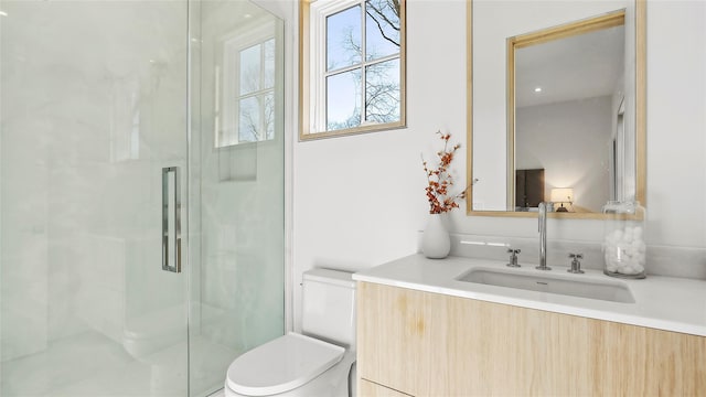 bathroom featuring vanity, toilet, and a shower with shower door