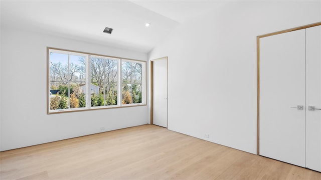 unfurnished bedroom featuring vaulted ceiling and light wood-type flooring