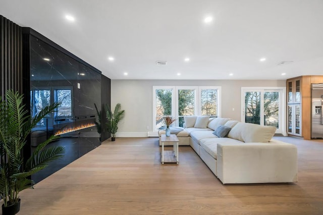 living room with a fireplace and light wood-type flooring