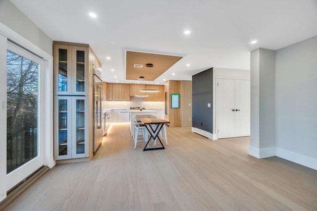 kitchen featuring stainless steel built in refrigerator, a kitchen bar, light brown cabinetry, light wood-type flooring, and a kitchen island