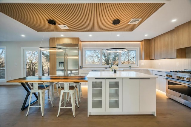 kitchen featuring stainless steel gas range, a center island, white cabinets, dark hardwood / wood-style flooring, and decorative backsplash