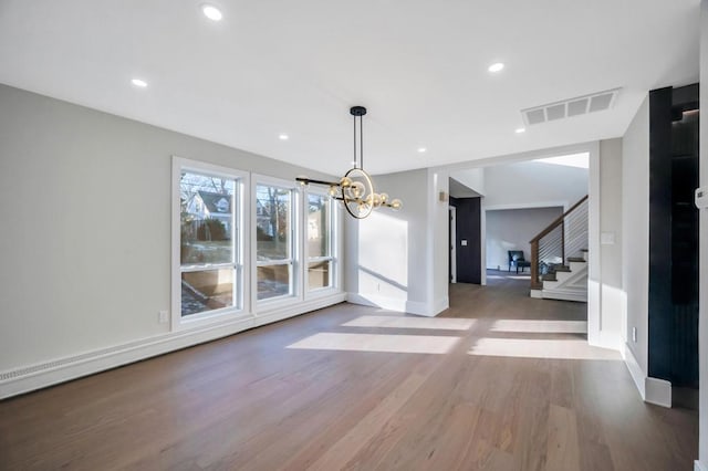 unfurnished dining area with wood-type flooring and a notable chandelier