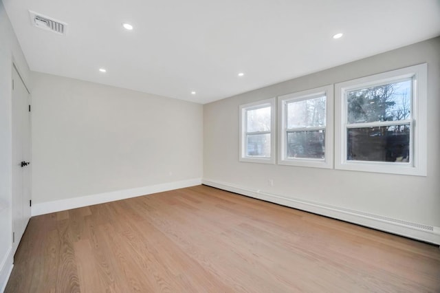 unfurnished room with baseboard heating, a healthy amount of sunlight, and light hardwood / wood-style floors