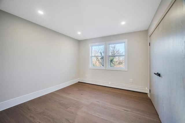 unfurnished room featuring hardwood / wood-style flooring and baseboard heating