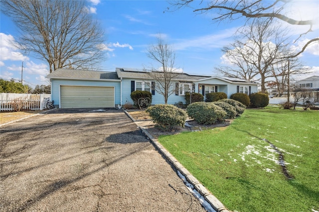 ranch-style home with a garage, a front yard, and solar panels