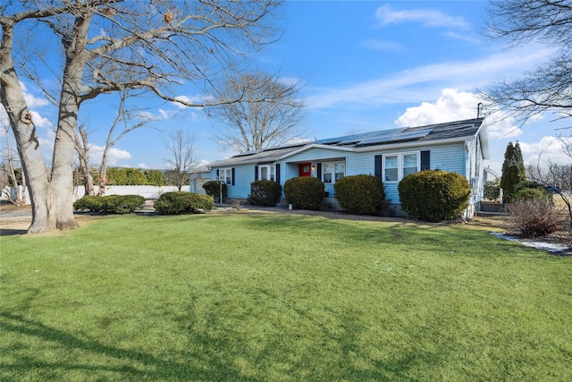 ranch-style home featuring a front lawn and solar panels