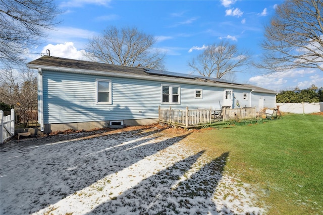 rear view of house with a yard and solar panels