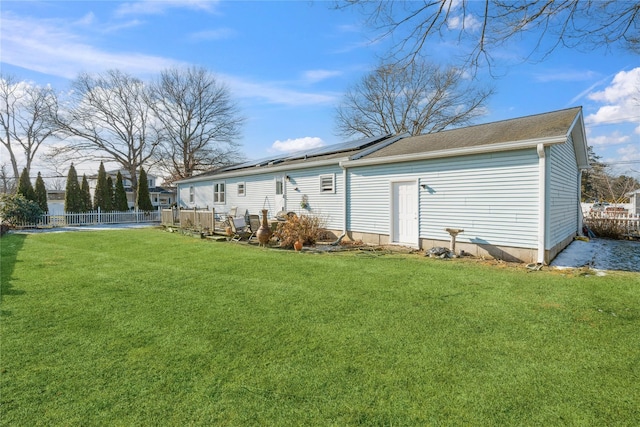 rear view of house featuring a lawn and solar panels