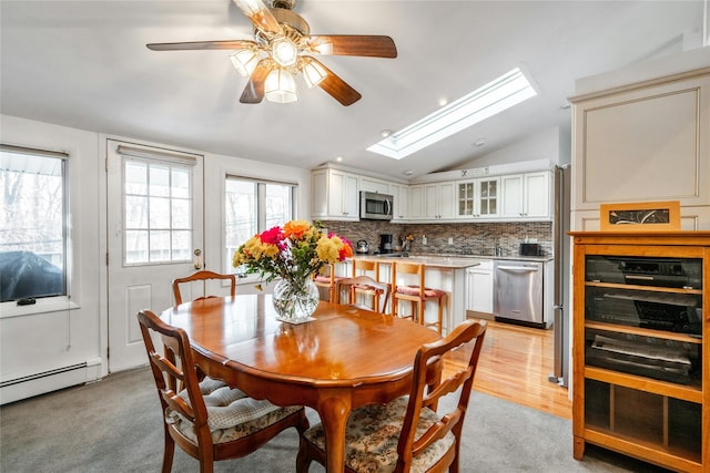 dining room featuring lofted ceiling with skylight, ceiling fan, and a baseboard radiator