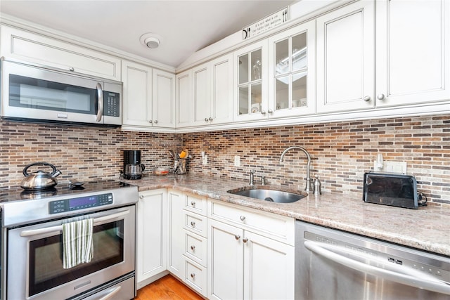 kitchen featuring appliances with stainless steel finishes, tasteful backsplash, sink, white cabinets, and light stone counters