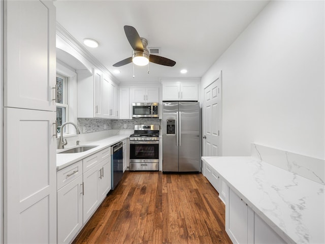 kitchen with sink, white cabinetry, appliances with stainless steel finishes, dark hardwood / wood-style floors, and light stone countertops