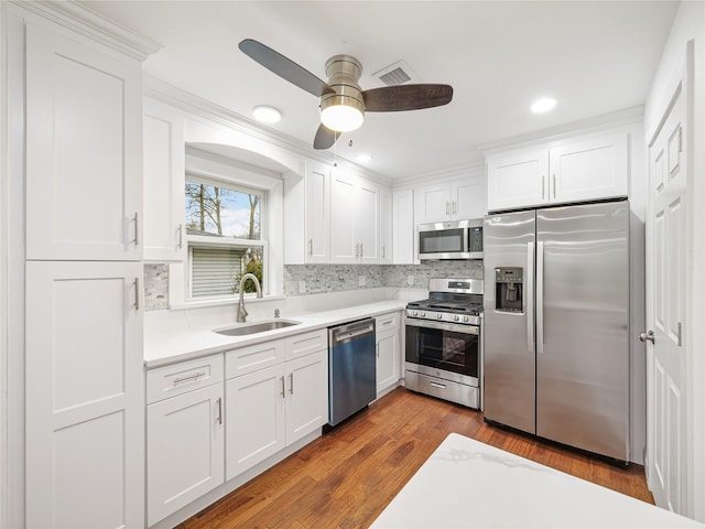 kitchen featuring sink, white cabinets, dark hardwood / wood-style flooring, backsplash, and stainless steel appliances