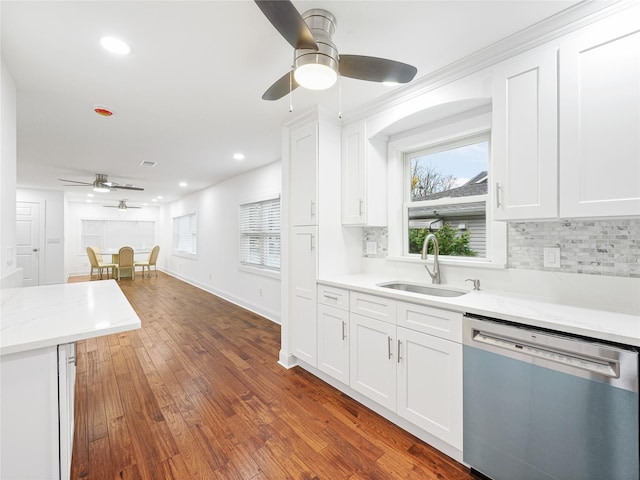 kitchen featuring light stone countertops, sink, stainless steel dishwasher, and white cabinets